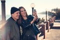 A young loving couple spends fun time by the sea and makes selfies. Man and woman have spring clothes