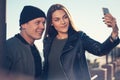 A young loving couple spends fun time by the sea and makes selfies. Man and woman have spring clothes