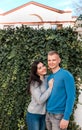 Couple standing near house with ivy fence.