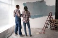 Young loving couple staring at their painted room, back view. Home renovation and relationship concept. Royalty Free Stock Photo
