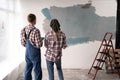 Young loving couple staring at their painted room, back view. Home renovation and relationship concept Royalty Free Stock Photo