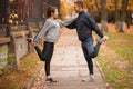 Young couple stretching leg muscles standing in a park and looking at each other. Royalty Free Stock Photo