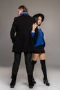 Studio shot of a beautiful young woman and man posing over a gray studio background.