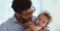 Young loving dad kissing, cuddling sweet little baby with adoration
