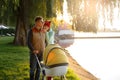 A young loving family walks by the lake with a stroller. Smiling parents couple with baby pram in autumn park. Love, parenthood, f Royalty Free Stock Photo