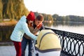 A young loving family walks by the lake with a stroller. Smiling parents couple with baby pram in autumn park look into cariage. L Royalty Free Stock Photo