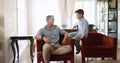 Father and little son lead carefree tattle seated on armchair