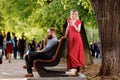 Young loving hipster couple eating ice cream outdoors at city crowded street. Stylish smiling bearded man on bench and Royalty Free Stock Photo