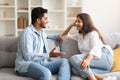 Young loving indian couple talking and flirting enjoying conversation at home, spending time together sitting on sofa