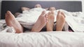 Young loving joyful couple play their feet under blanket while wake up in bed in the morning Royalty Free Stock Photo