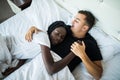 Young loving mixed race couple sleeping in bed, they are hugging, top view Royalty Free Stock Photo