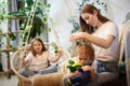 Young loving mom making ponytail to little preschool daughter and adult sister on background in living room. Mother Royalty Free Stock Photo