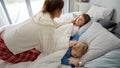 Young loving mother caressing her two sons sleeping in bed at morning. Concept of family happiness, relaxing at home, having fun Royalty Free Stock Photo