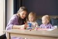 Caring young mom teaching how to draw her two little kids Royalty Free Stock Photo