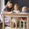 Caring young mom teaching how to draw her two little kids Royalty Free Stock Photo