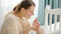 Young loving mother holding and kissing tiny feet of her little baby lying in crib. Concept of parenting, family Royalty Free Stock Photo