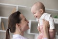 Young loving mother lifts her baby enjoy playtime at home Royalty Free Stock Photo