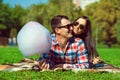 Young loving smiling happy couple in sunglasses lying on the green lawn