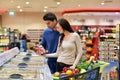 Young lucky couple shopping for fresh food in the supermarket -