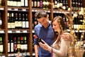 Young lucky couple shopping for wine in the supermarket Royalty Free Stock Photo