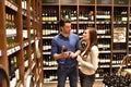 Young lucky couple shopping for wine in the supermarket