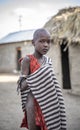 Young maasai kid in traditional clothing in his home boma village