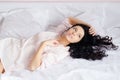Young magic beautiful charming woman in white shirt lying on the bed & looking in window on white background closeup portrait