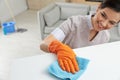 Young maid dusting furniture with rag