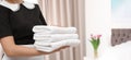 Young maid holding stack of fresh towels in hotel room, view with space for text. Banner design Royalty Free Stock Photo