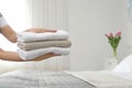 Young maid holding stack of fresh towels in hotel room Royalty Free Stock Photo