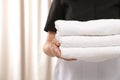 Young maid holding stack of fresh towels in hotel room Royalty Free Stock Photo