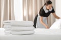 Young maid making bed in hotel room, focus on stack Royalty Free Stock Photo