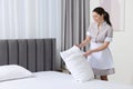 Young maid making bed in hotel room. Space for text Royalty Free Stock Photo