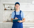 Young maintenance worker noting down cleaning tasks in home kitchen