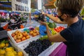 Young Malasian woman checks the quality of the grapes before buying. The girl is wearing face mask because of the virus crisis.