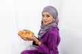 Muslim girl celebrates end of Ramadan, in purple dress, and holding food, waist up portrait Royalty Free Stock Photo