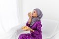 Muslim Malay girl celebrates end of Ramadan, in purple dress with hijab, and holding food Royalty Free Stock Photo