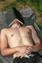 Young male adult laying in the sun sleeping under a book Royalty Free Stock Photo