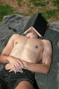 Young male adult laying in the sun sleeping under a book Royalty Free Stock Photo