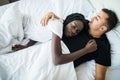 Young male and african female in love sleeping and embracing in bed on bedroom at home. View from above. Interracial Couple Royalty Free Stock Photo