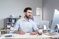 Young male architect, designer making drawings and project on whatman paper on desk in his office. Sitting at a table, with a Royalty Free Stock Photo