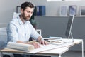 Young male architect, designer making drawings and project on whatman paper on desk in his office. Sitting at a table, with a Royalty Free Stock Photo