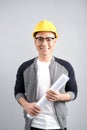 Young male architect wearing helmet and holding blueprints, isolated on gray background Royalty Free Stock Photo