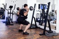 Young male athlete with barbell flexing muscles and making shoulder press squat on intense electrical muscle stimulation training