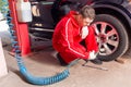 Young male auto mechanic checking the air pressure of a tyre Royalty Free Stock Photo