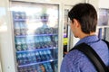 Young male backpacker tourist choosing a snack or drink at vending machine. Vending machine with man