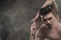 A young male ballet dancer with black leggings and a naked torso performs dance moves against a gray grunge background Royalty Free Stock Photo