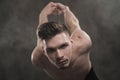 A young male ballet dancer with black leggings and a naked torso performs dance moves against a gray grunge background Royalty Free Stock Photo