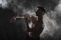 A young male ballet dancer with black leggings and a naked torso performs dance moves against a gray grunge background Royalty Free Stock Photo