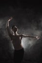 A young male ballet dancer with black leggings and a naked torso performs dance moves against a gray grunge background Royalty Free Stock Photo